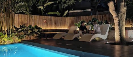 A poolside area with lounge chairs and a wooden fence.