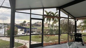 A covered outdoor area with large windows, a patio, and a view of a marina and residential area. - Gulf Access Getaway in Punta Gorda (Punta Gorda)