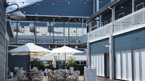 An outdoor patio with tables and chairs, umbrellas, and a menu stand. - Gulf Access Getaway in Punta Gorda (Punta Gorda)