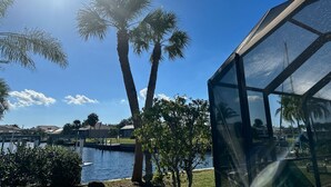 A clear view of a modern building with large glass windows, a body of water, and palm trees in the background. - Gulf Access Getaway in Punta Gorda (Punta Gorda)