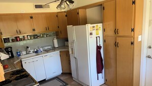 A compact kitchen with wooden cabinets, a white refrigerator, a stove, and a sink. - NEAR CAMPUS! Choice KING or QUEEN BEDS w fresh interior paint & great parking! (College Station)