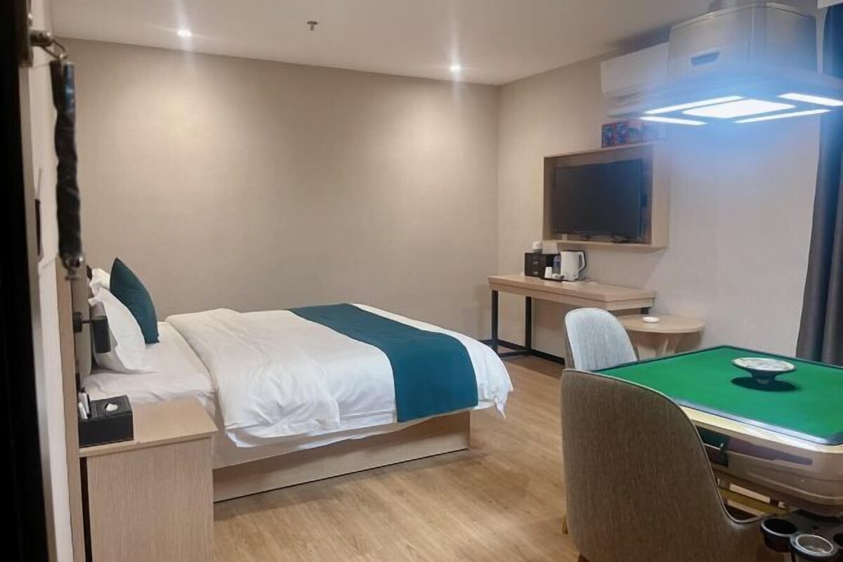 Ein Hotelzimmer mit einem Bett, einem Schreibtisch mit Stuhl, einem Fernseher und einem Billardtisch.