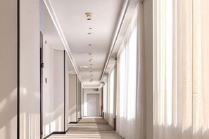 A long, narrow hotel corridor with a ceiling light fixture, a carpeted floor, and a door at the end. - Shell Hotel (Zhuhai Doumen Daxin Xinduhui) (Zhuhai)