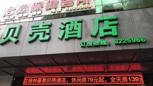 A hotel sign with green lettering and a red neon sign below it. - Shell Hotel (Zhuhai Doumen Daxin Xinduhui) (Zhuhai)
