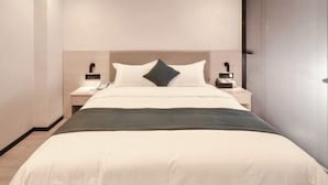 A modern hotel room with a large bed, bedside tables, a nightstand, and a wardrobe. - Shell Hotel (Zhuhai Doumen Daxin Xinduhui) (Zhuhai)