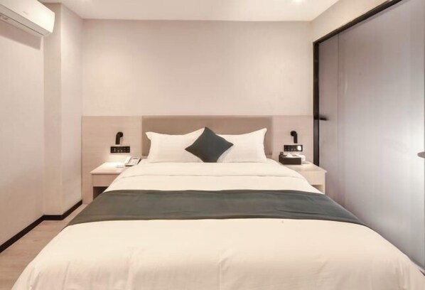 Ein modernes Hotelzimmer mit einem großen Bett, Nachttischen, einem Beistelltisch und einem Kleiderschrank.