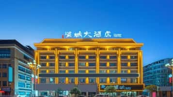 A multi-story hotel with a prominent sign, a well-lit facade, and a parking area in front.