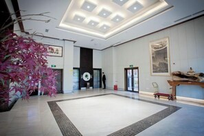 Experience the stylish lobby with a large potted plant, wooden table, and framed artwork.