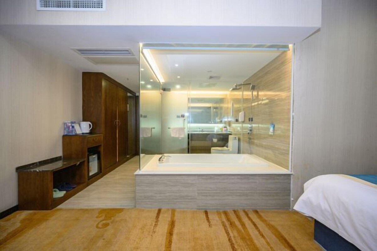 A modern hotel room with a large bathtub, a wooden cabinet, and a glass-enclosed shower area.