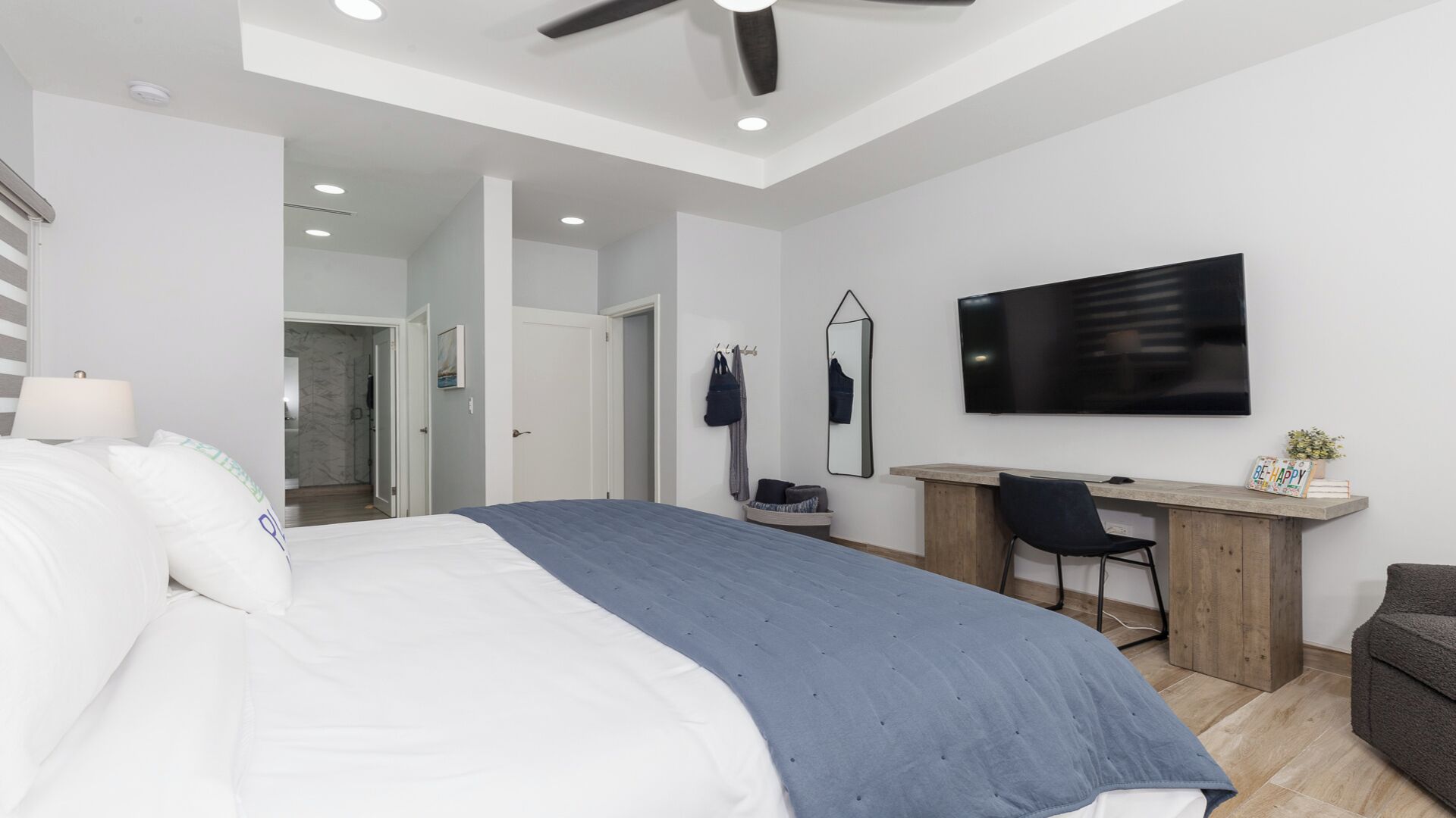 A modern bedroom with a large bed, a desk, and a TV.