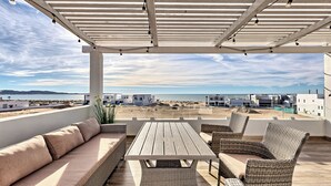 Un espacio de estar al aire libre cubierto con vistas a la playa y edificios.