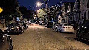 A nighttime street scene with parked cars and houses. - Fidelia Room Fuchsite (Irvington)