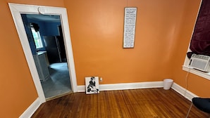 A room with orange walls, wooden flooring, a ceiling fan, and a motivational quote on the wall. - Fidelia Room Fuchsite (Irvington)
