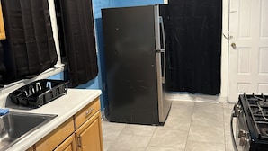 A kitchen with a black refrigerator, a stove, and a sink. - Fidelia Room Fuchsite (Irvington)