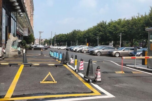 Un estacionamiento con autos, una estatua y un edificio con un letrero.