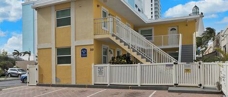 A multi-story building with a yellow facade, a staircase, and a gated entrance.