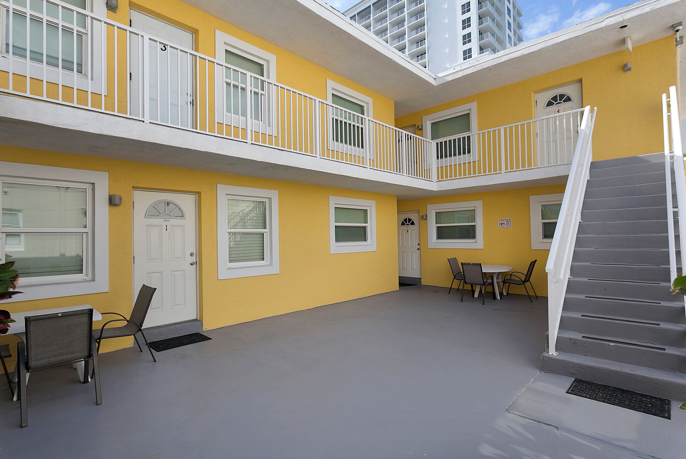 A yellow building with white railings and a staircase.