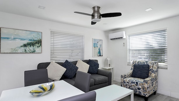 A modern living room with a grey sofa, a patterned armchair, a white coffee table, and a ceiling fan. - ULTRA exciting Apartment at Boardwalk  (Hollywood)