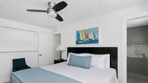 A bedroom with a bed, a ceiling fan, a painting of sailboats, and a bathroom with a marble shower. - ULTRA exciting Apartment at Boardwalk  (Hollywood)