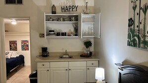 A compact kitchen with white cabinets, a coffee maker, and a sink. Above the sink, there is a 'HAPPY' sign. - Comfortable, Within Walking Distance To The Beaches 2217
 (Hallandale Beach)