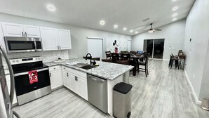 A modern kitchen with white cabinets, stainless steel appliances, and a granite countertop.