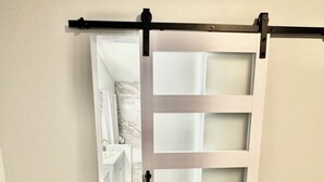 A sliding door with a handle, leading to a room with a marble backsplash and a white dresser.