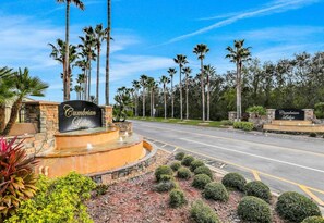 A road leading to a property named 'Cumberland Lakes' with a landscaped area featuring palm trees and a fountain. - Charming 4-bedroom house with pool,WiFi, AC in Kissimmee near Disney (Kissimmee)