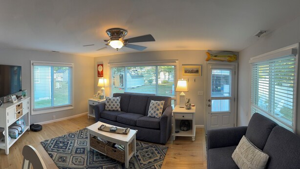 A living room with a gray sofa, a coffee table, a TV on a stand, and a ceiling fan. - Charming 3-bedroom house in beautiful Cape May, NJ (Cape May)