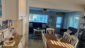 A kitchen with a dining table, chairs, and a refrigerator. There is a window with blinds and a ceiling fan. - Charming 3-bedroom house in beautiful Cape May, NJ (Cape May)