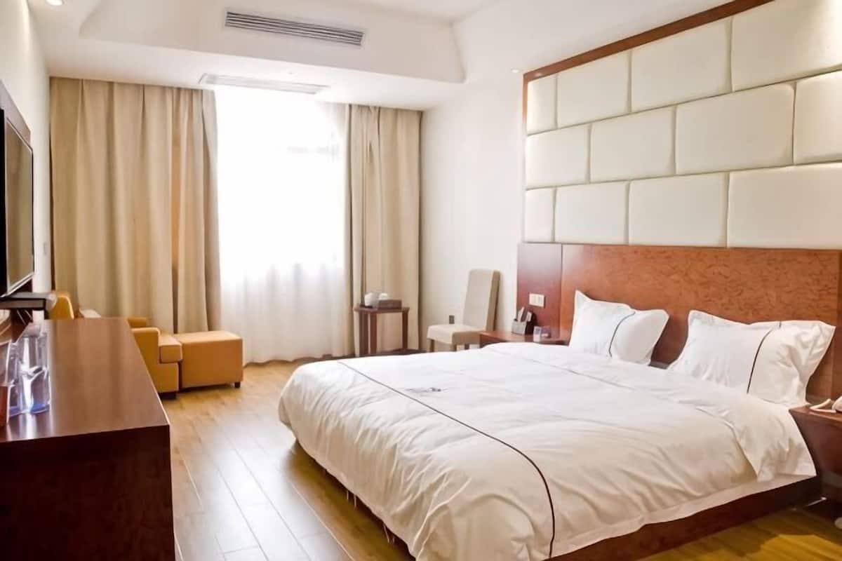 Une chambre d’hôtel avec un grand lit, un bureau, une chaise et un téléviseur.