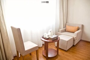 A room with a chair, a small table with a tray, a sofa, and a window with curtains. - Fuhao Hotel Suichuan (Suichuan)
