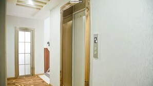 A hallway with carpet, an elevator, a door, and a wall-mounted control panel. - Fuhao Hotel Suichuan (Suichuan)