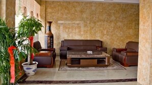 A lobby with a marble floor, a brown sofa set, a coffee table, and a potted plant. - Fuhao Hotel Suichuan (Suichuan)