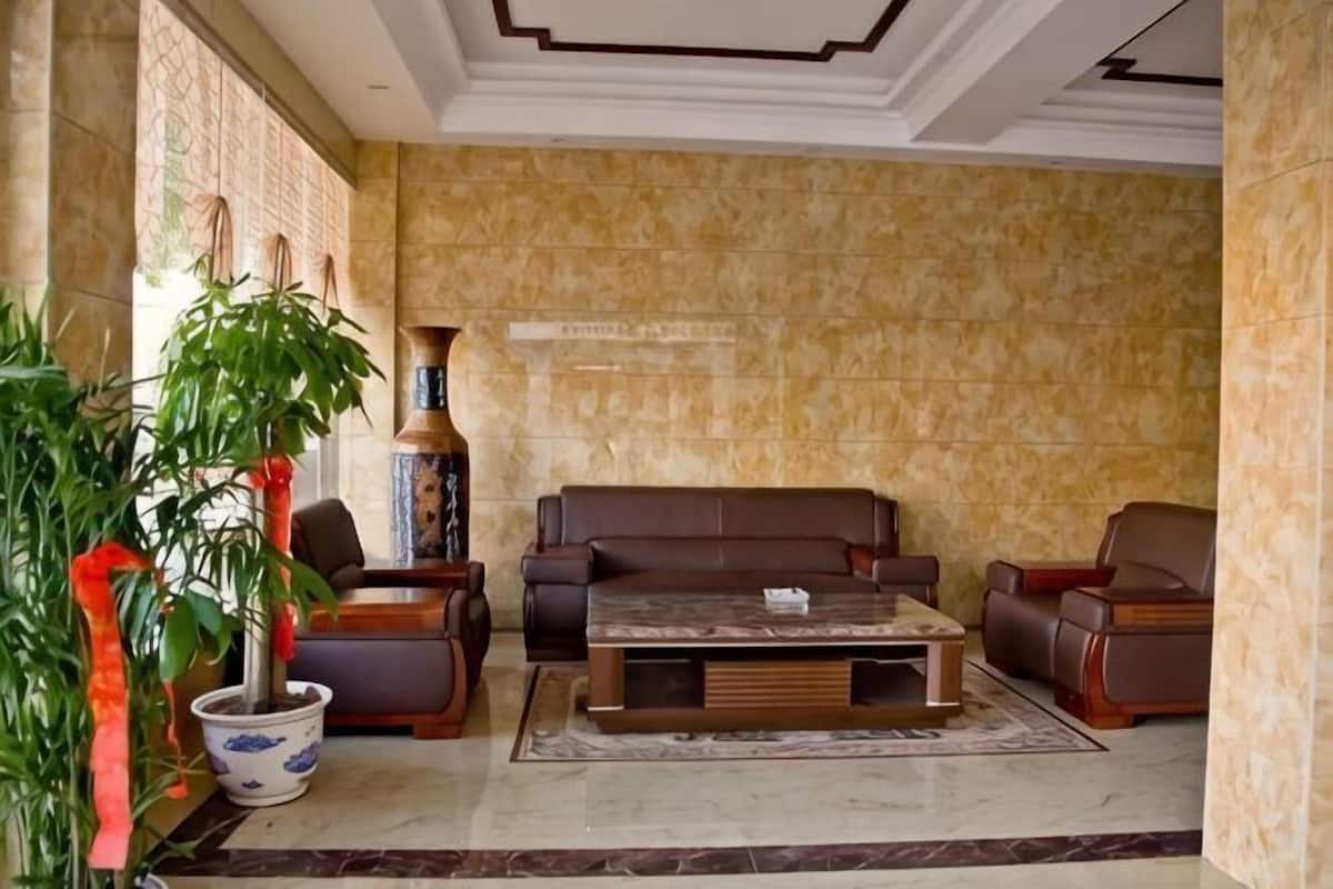 Un hall d’entrée avec un sol en marbre, un ensemble de meubles de salon marron, une table basse et une plante en pot.