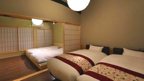 Une chambre avec deux lits, un plancher en bois et un paravent japonais traditionnel en papier.
