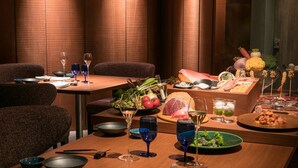 Un restaurant aux murs lambrés, avec des tables dressées, ornées de verres à vin, d’assiettes et d’une variété de plats, notamment des fruits de mer et des légumes.