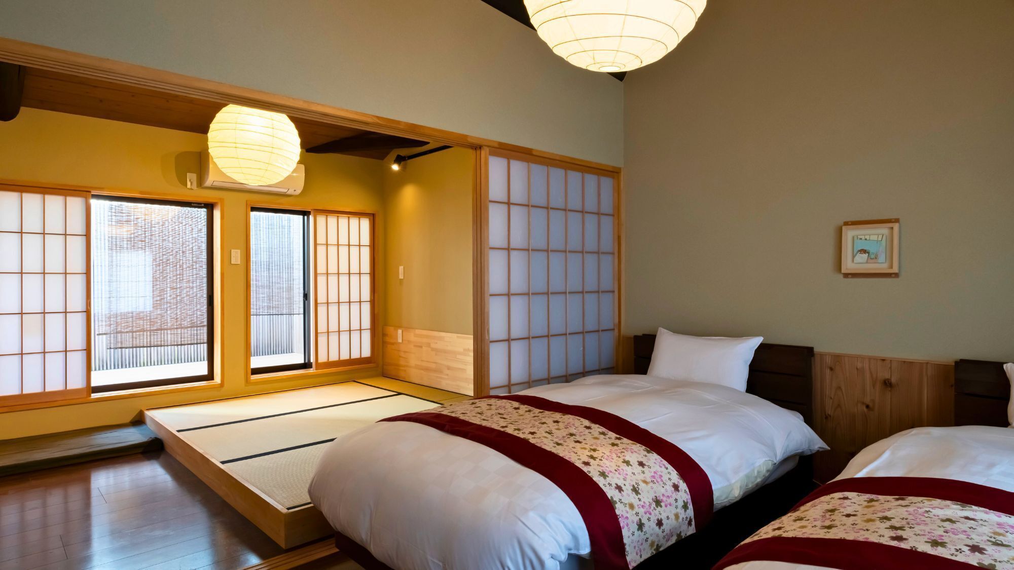 Ein traditioneller japanischer Raum mit Tatami-Böden, Schiebetüren im Shoji-Stil und einem Bett mit floralem Überwurf.
