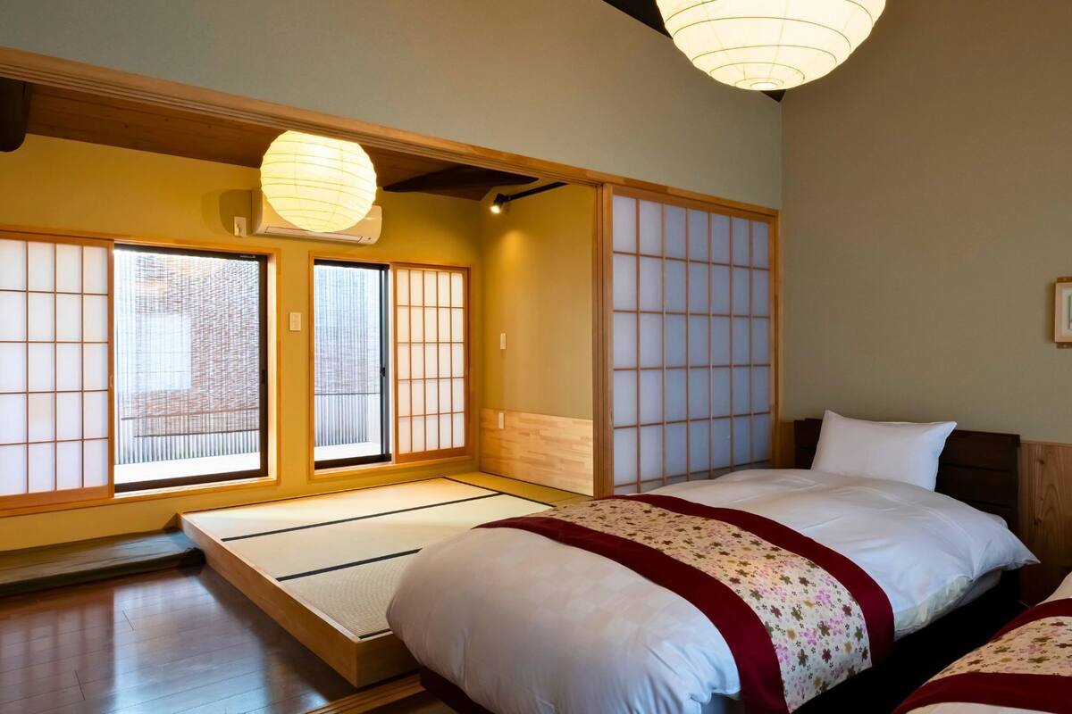 Ein traditioneller japanischer Raum mit Tatami-Böden, Schiebetüren im Shoji-Stil und einem Bett mit floralem Überwurf.