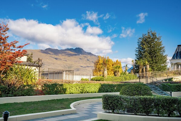 A landscaped courtyard with a pathway, a staircase, and a mountain backdrop. - THE BEACON - TOWN CENTER APARTMENT 622 (Queenstown)