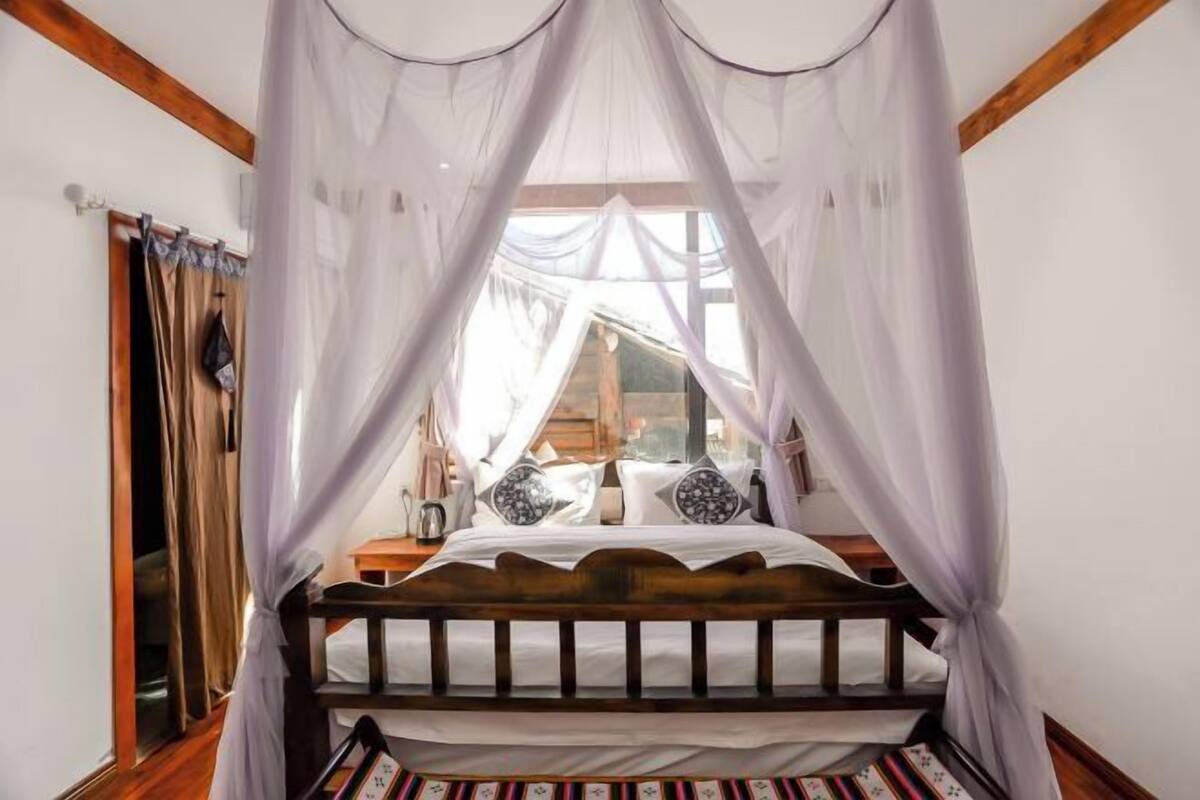 Un dormitorio con una cama de madera, ropa de cama blanca y dosel.