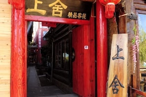 A wooden entrance with Chinese characters, a red door, and a wooden sign with characters.