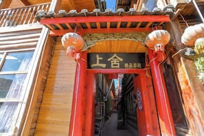 Entrada de un edificio tradicional de madera con un arco rojo y un letrero encima.