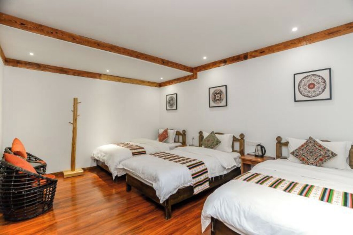 Habitación de hotel con dos camas, vigas de madera en el techo y un ventanal grande.