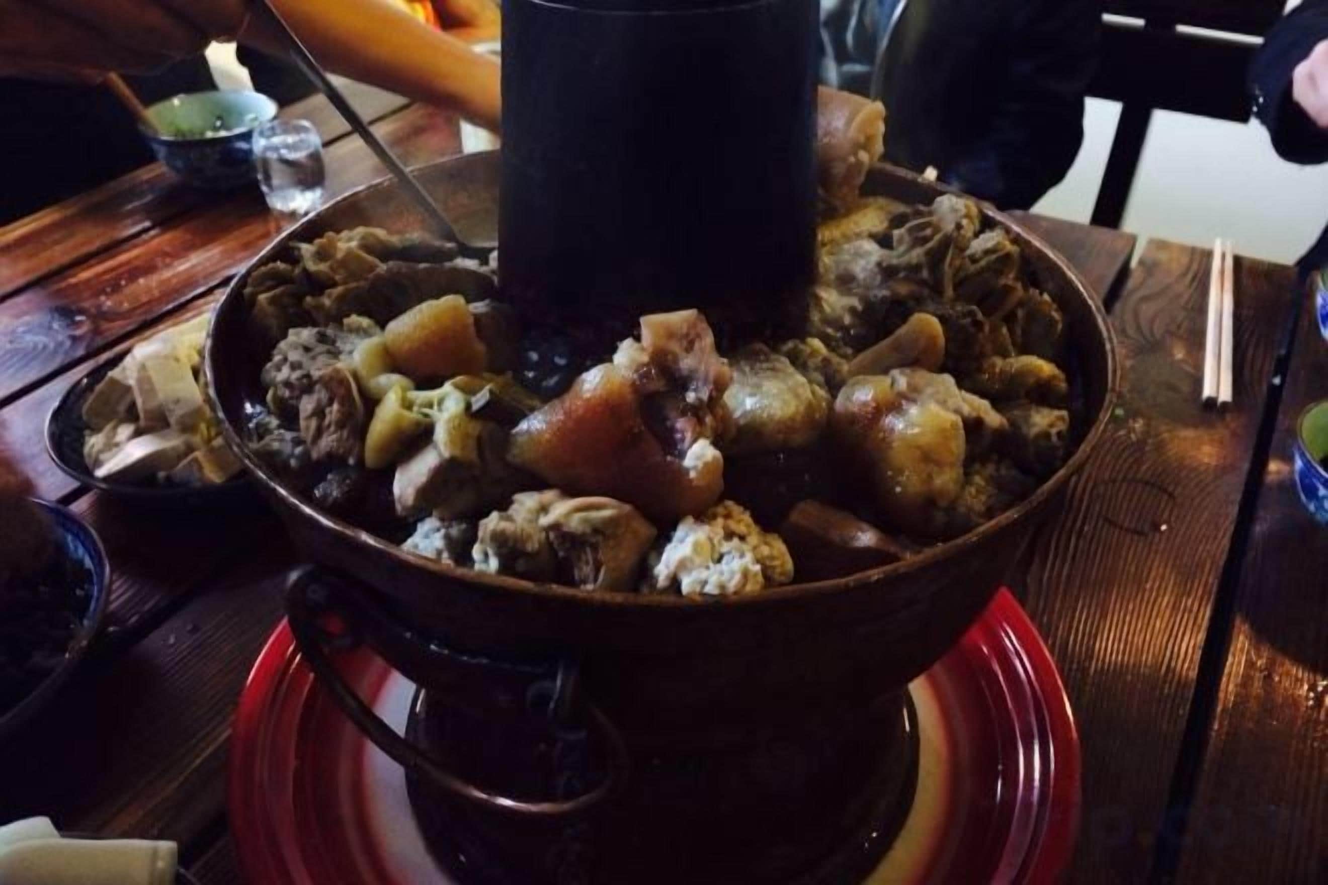 Un plato rojo con una olla caliente y diversos ingredientes.