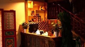 A bar area with a wooden counter, shelves with bottles, and a staircase with a railing.