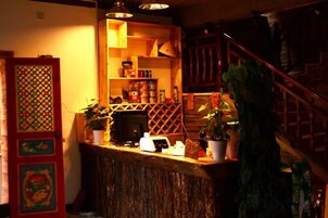 A bar area with a wooden counter, shelves with bottles, and a staircase with a railing.