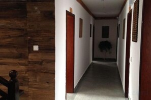 A hallway with wooden walls and doors, leading to a room with a plant. - Luguhu Yangguang Clubhouse (Ninglang)