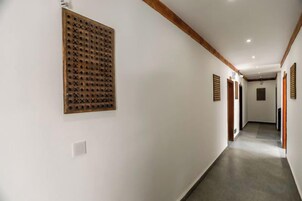 Un pasillo con una viga de techo de madera, un aplique en la pared y una puerta al final.