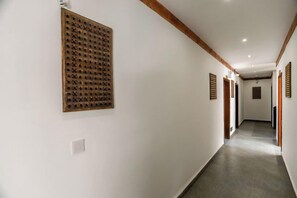 Un pasillo con una viga de techo de madera, un aplique en la pared y una puerta al final.