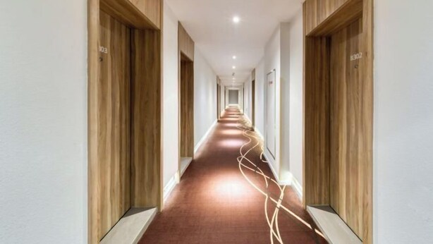 Un largo y estrecho pasillo con paneles de madera en las paredes y una alfombra roja.